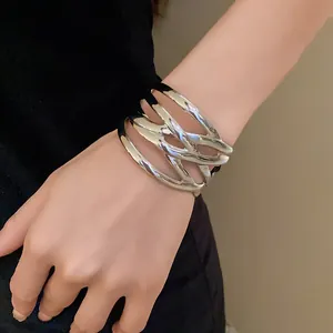 Detailed view of an oversized silver-finish intertwined metal cuff bracelet on wrist.
