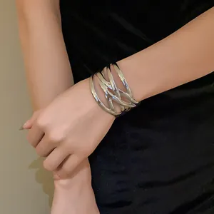 Close-up detail of oversized silver multi-strand metal cuff bracelet on woman wrist