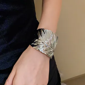 Macro detail of a silver metallic cuff bracelet featuring an intricate leaf vein texture