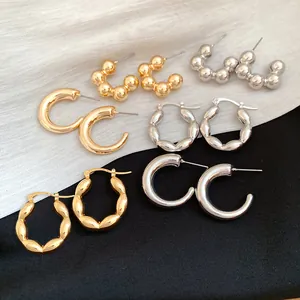 Multiple styles of gold and silver metallic hoop earrings on black and white fabric