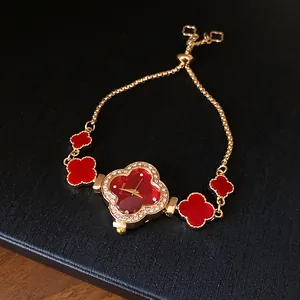 Detailansicht der roten Kleeblatt-Armbanduhr mit Gold-Finish und glänzenden Strasssteinen