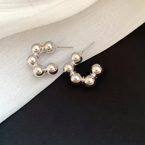 Close-up detail of silver beaded C-shaped hoop earrings on black and white fabric
