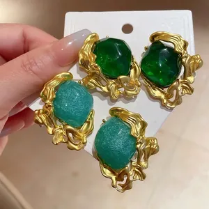 Elegant vintage emerald and mint green stud earrings with ornate gold molten frames