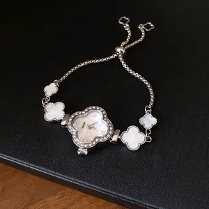 Detailansicht einer eleganten Kleeblatt-Armbanduhr mit Strass und weißen Einsätzen