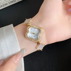 Nahaufnahme einer goldfarbenen Armbanduhr mit vierblättrigem Kleeblatt und Strass