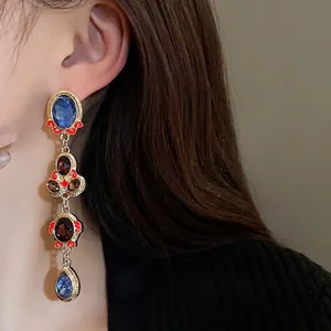 Vintage style long dangling earrings with blue gems and gold metal accents for women