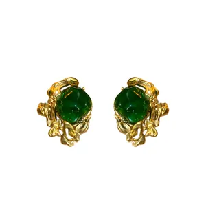 Vintage style emerald green stud earrings with ornate gold-tone scrollwork borders.