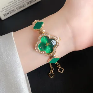 Nahaufnahme eines goldenen Armbanduhr-Sets mit grünen vierblättrigen Kleeblatt-Blüten.