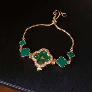 Nahaufnahme einer luxuriösen grünen Kleeblatt-Armbanduhr mit Diamanten und Goldkette.