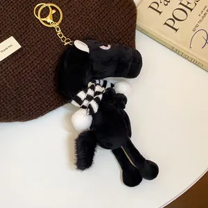 Close-up view of a black plush horse keychain charm featuring a cute striped scarf
