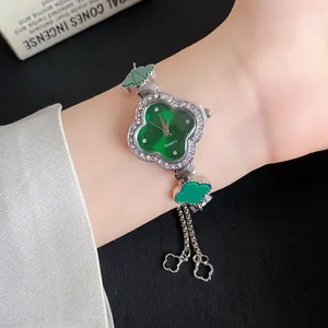 Detailansicht einer grünen Kleeblatt-Uhr mit Strassverzierung am weiblichen Handgelenk