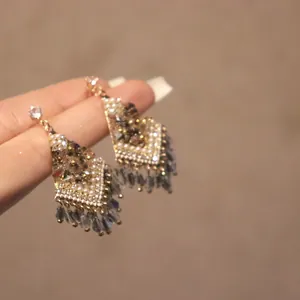 Λεπτομερής προβολή από κομψά μποέμ σκουλαρίκια με κρυστάλλινες φούντες και στρας