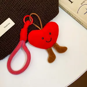 Close-up detail of a plush red heart-shaped keychain with a smiley face and rope lanyard