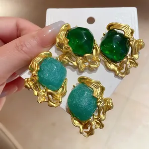 Close-up of vintage emerald green and turquoise stud earrings with gold molten frames