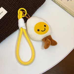Detailed view of a cute plush fried egg keychain featuring a smiley face and yellow cord loop