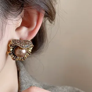 Vintage style gold-tone shell shaped stud earrings with brown pearl and rhinestones