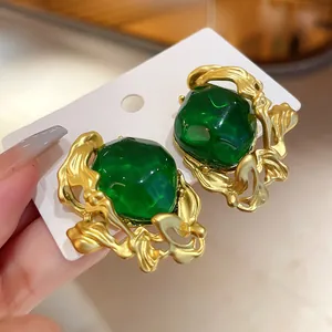 Close-up of vintage emerald stud earrings with textured gold palace-style frames