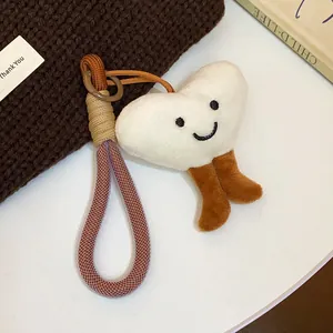 Close-up of cute plush heart pendant keychain with smiling face and braided cord loop.