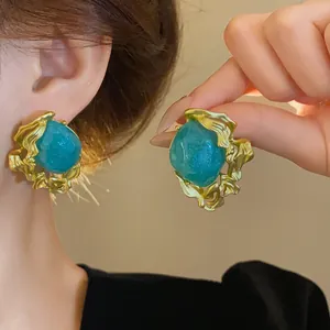 Close-up detail of vintage emerald court style stud earrings with irregular gold molten frame