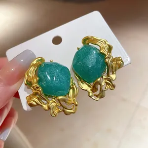 Detailed view of vintage emerald green studs with irregular matte gold frames