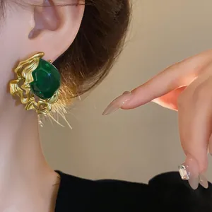 Close-up detail of vintage style emerald green earring with irregular gold metal texture