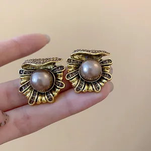 Vintage gold shell stud earrings with pearl and rhinestone detail in detail view.