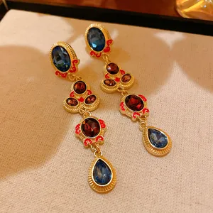 Vintage gold drop earrings with blue and red crystals, elegant jewelry detail view.