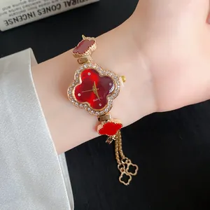 Nahaufnahme einer eleganten Blumenuhr mit rotem Acetat und goldfarbenem Strassarmband.