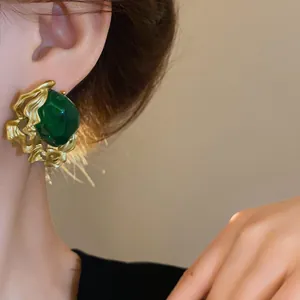 Close-up detail of vintage emerald green stud earring with textured gold frame