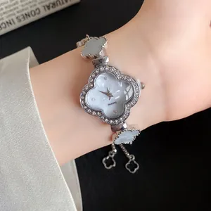 Nahaufnahme einer silbernen Strass-Blumenuhr mit Acetat-Klee-Gliedern am Handgelenk