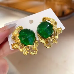 Macro detail of vintage emerald green gemstone earrings with molten gold frame.