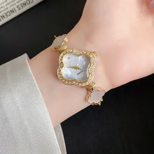Detailansicht einer eleganten goldenen Quarzuhr in Kleeblattform mit Strasssteinen