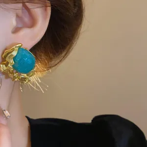 Macro detail of a vintage style emerald green gemstone earring with gold textured frame