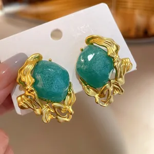 Close-up of vintage emerald green stud earrings with irregular molten gold frames