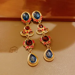 Detailed view of vintage gold earrings with blue and red stones, retro jewelry