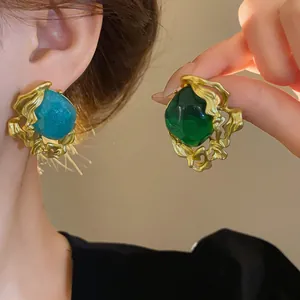 Close-up of vintage emerald and teal palace style earrings with gold textured frames
