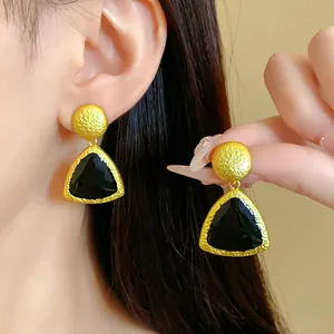Close-up of vintage geometric enamel drop earrings with a textured gold finish for women