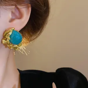 Detailed macro shot of vintage-style gold earrings with an emerald green stone