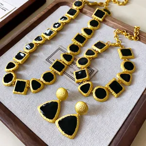 Vintage gold-tone jewelry set with black geometric enamel detailing on a rustic wooden tray.
