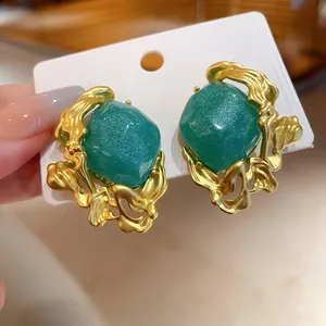 Detailed close-up of vintage emerald green earrings with a shimmering gold molten frame