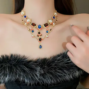 Detailed view of vintage teardrop necklace with blue rhinestones and pearls on model