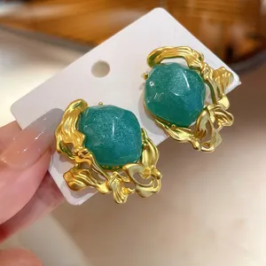 Detail showing vintage emerald green stud earrings with ornate gold-toned metal design.
