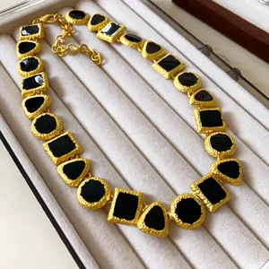 Detail shot of vintage palace style gold necklace with black geometric enamel pieces.
