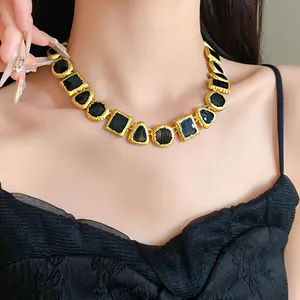 Close-up detail of a vintage gold and black geometric enamel necklace worn by an Asian model.