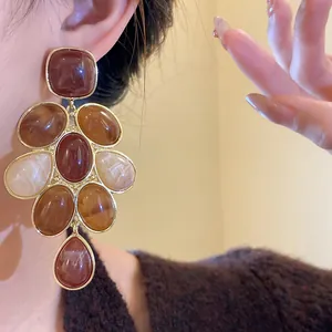 Dettaglio ravvicinato di orecchini vintage in resina marrone indossati da una modella