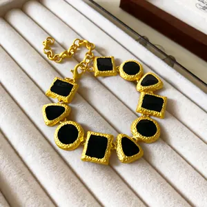 Close-up of vintage style geometric drip-oil necklace with gold and black segments