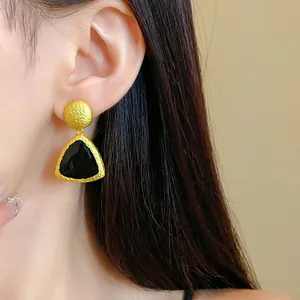 Detail shot of elegant vintage gold textured earrings featuring a black triangle enamel inlay