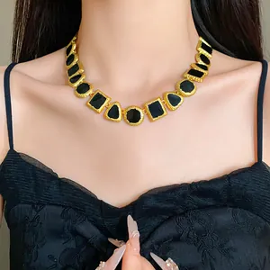 Macro detail of a vintage geometric enamel collar necklace with gold-textured metal and black resin.