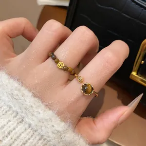 Vue détaillée d'une bague perlée en œil de tigre rétro et d'une bague dorée sur la main.