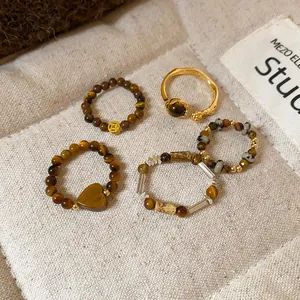 Détail de cinq bagues en perles d'œil de tigre et pierres, style ethnique vintage